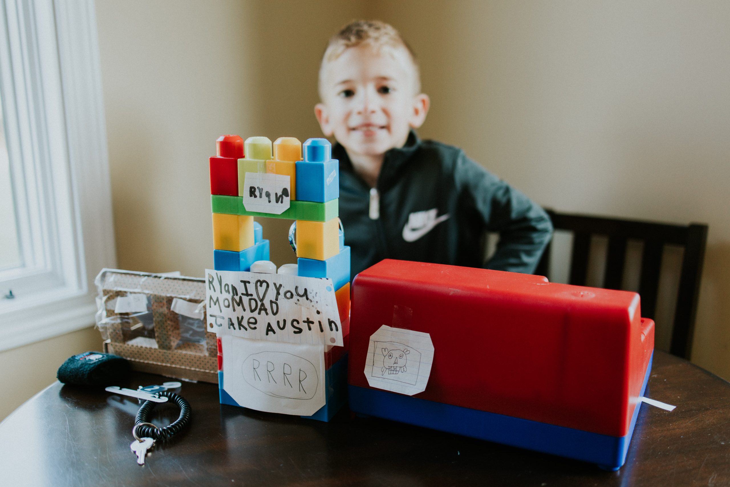 A smiling boy sitting at a table with toys in front of him