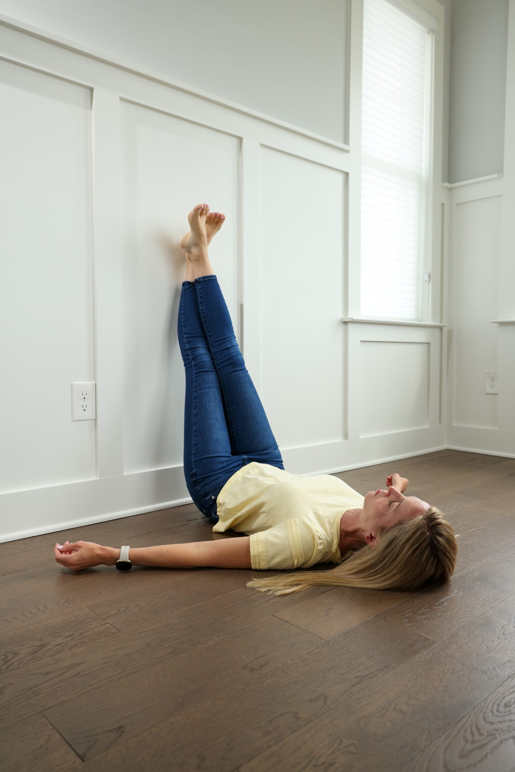 Kerri lying on the floor with her legs straight against the wall.